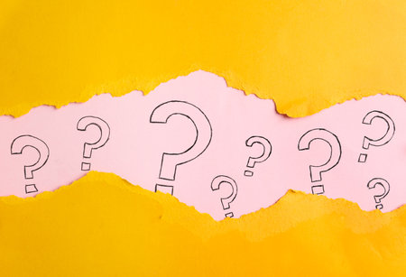 Question marks on pink background, view through hole in yellow paperの写真素材