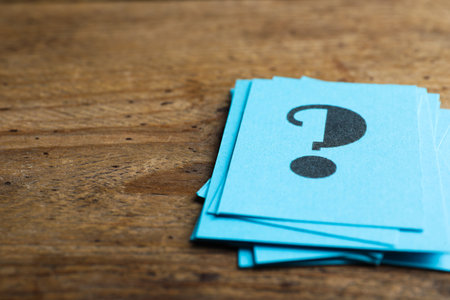 Blue paper cards with question mark on wooden background, closeup. Space for textの写真素材