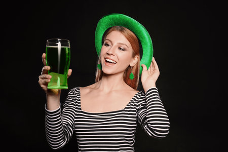 Young woman with green beer on black background. St. Patrick's Day celebrationの写真素材