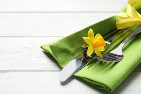 Cutlery set with beautiful narcissus on white wooden table, closeup. easter celebrationの写真素材
