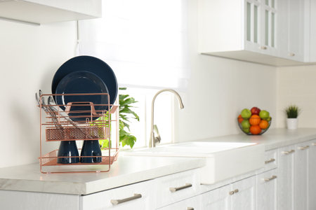 Drying rack with clean dishes on countertop in kitchen. Space for textの写真素材