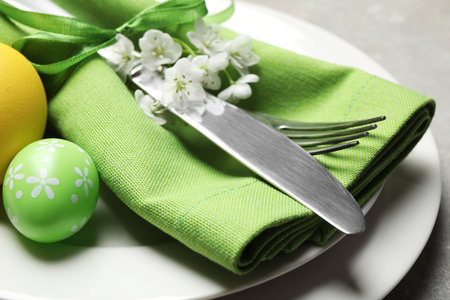 Festive Easter table setting with floral decor on gray background, closeup