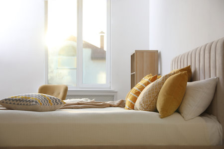 Comfortable bed with soft pillows in stylish room interiorの写真素材