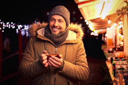 Happy man with mulled wine at winter fairの写真素材