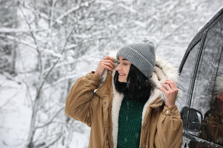 Young woman wearing warm clothes outdoors on snowy day. winter holidays