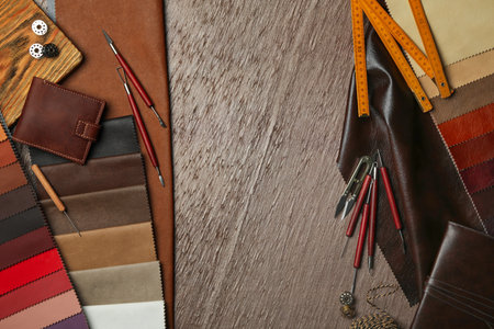 Flat lay composition with leather samples and tools on brown table. Space for text