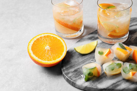 Ice cubes with orange and mint on light gray tableの写真素材