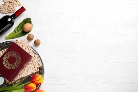 Flat lay composition with symbolic Pesach (Passover Seder) items on white wooden table, space for...