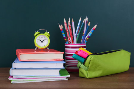 Composition with stationery and alarm clock on table near chalkboard. Doing houseworkの写真素材