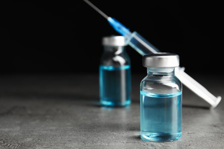 Vials and syringe on gray table. Vaccination and immunizationの写真素材