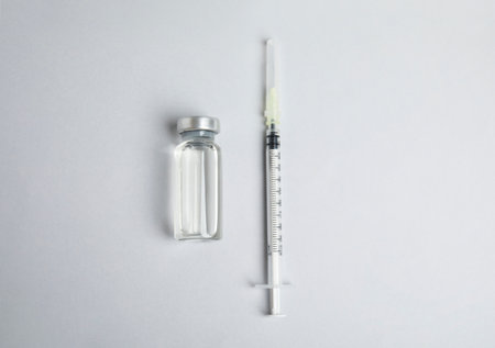 Vial and syringe on light background, flat lay. Vaccination and immunizationの写真素材