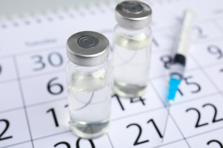 Vial and syringe on calendar, closeup. Vaccination and immunizationの写真素材