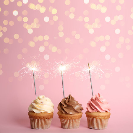 Birthday cupcakes with sparklers on pink backgroundの写真素材