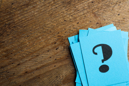 Blue paper cards with question mark on wooden background, top view. Space for textの写真素材