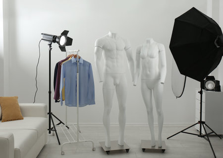 Ghost mannequins, clothes and professional lighting equipment in modern photo studioの写真素材