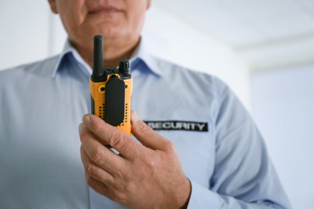 Professional security guard with portable radio set indoors, closeupの写真素材