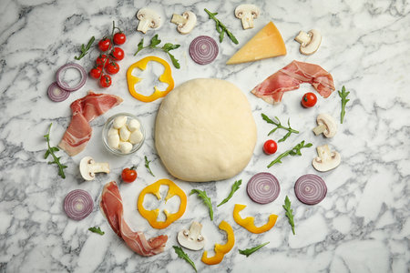 Flat lay composition with dough and fresh ingredients for pizza on white marble tableの写真素材