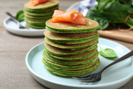 Tasty spinach pancakes with salmon on wooden table, closeupの写真素材