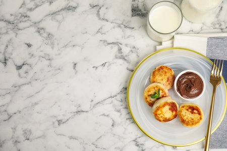 Delicious cottage cheese pancakes with chocolate paste on white marble table, flat lay. Space for textの写真素材