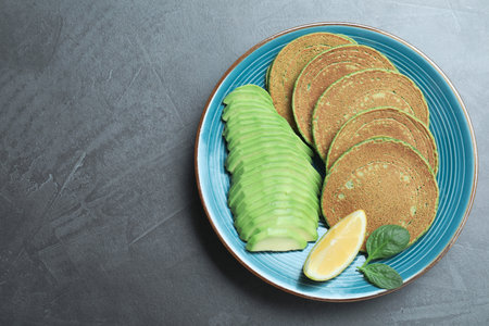 Tasty spinach pancakes served on gray table, top view. Space for text