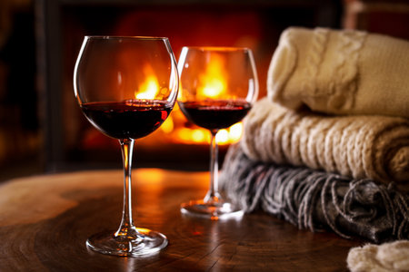 Glasses of wine, knitwear and blurred fireplace on backgroundの写真素材
