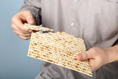 Man with Matzo on gray background, closeup. Pesach (Passover) celebration