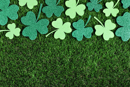 Flat lay composition with clover leaves on green grass, space for text. St. Patrick's Day...