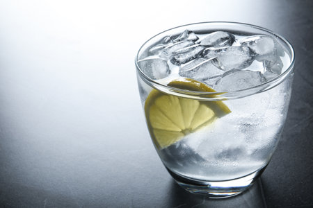 Water with ice cubes and lemon on gray table, closeup. Space for textの写真素材