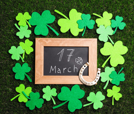 Flat lay composition with horseshoe and chalkboard on grass. St. Patrick's Day celebration