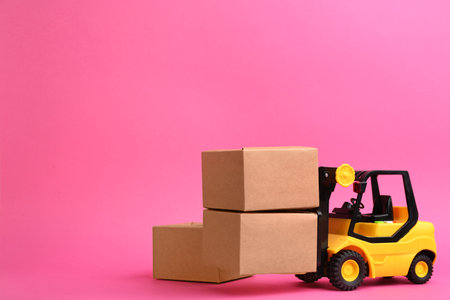 Forklift model and cardboard boxes on pink background, space for text. Courier serviceの写真素材