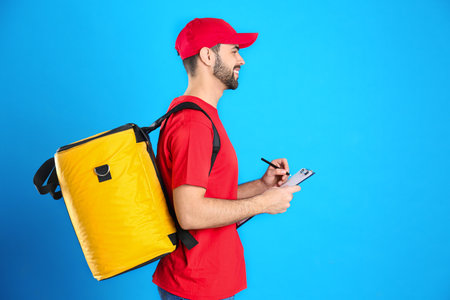 Courier with thermo bag and clipboard on light blue background, space for text. food delivery...