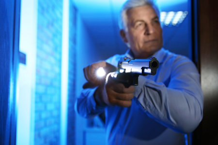 Professional security guard with gun checking dark room, focus on handの写真素材
