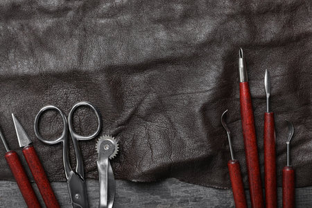Leather sample and craftsman tools on gray stone background, flat lay