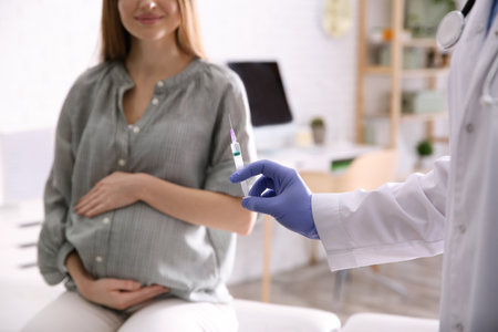 Doctor giving injection to pregnant woman in hospital, closeup. vaccination conceptの写真素材