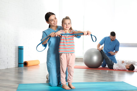 Orthopedists working with little children in hospital gymの写真素材