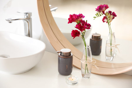 Beautiful spring freesia flowers on countertop in bathroomの写真素材
