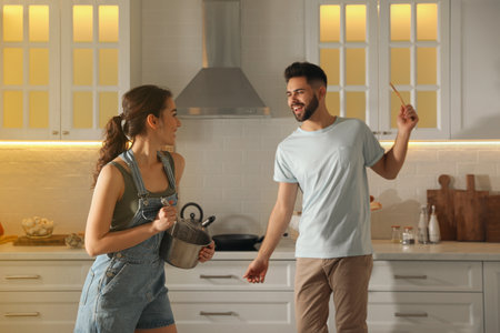Lovely young couple dancing while cooking together in the kitchenの写真素材