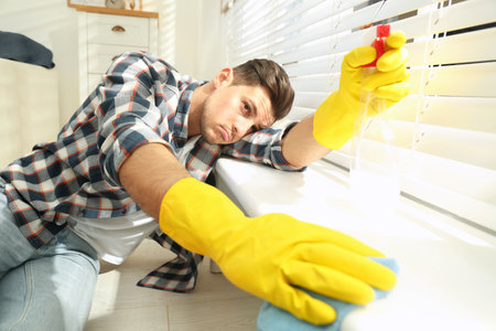 Lazy man procrastinating while cleaning at home