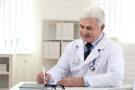 senior doctor working at table in officeの写真素材