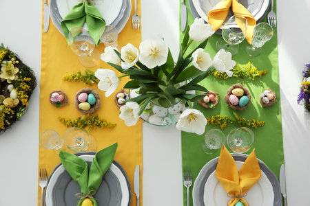 Festive Easter table setting with beautiful tulips and eggs, flat lay