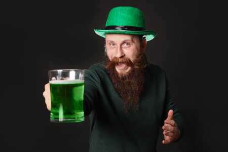 Bearded man with green beer on black background. St. Patrick's Day celebrationの写真素材