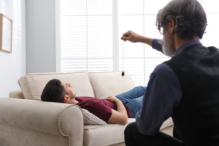Psychotherapist using pendulum during hypnotherapy session in office
