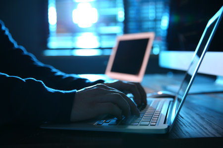 Hacker with laptop in dark room, closeup. cybercrime