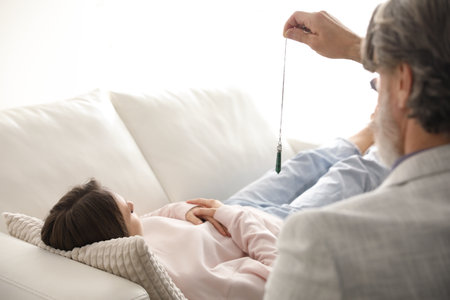 Psychotherapist using pendulum during hypnotherapy session in officeの写真素材