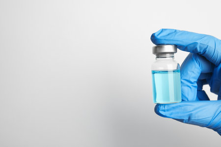 Doctor holding vial with medication on white background, closeup view and space for text. Vaccination and immunizationの写真素材