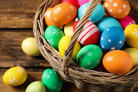 Colorful Easter eggs in basket on wooden background, closeup