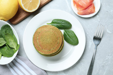 Tasty spinach pancakes served on light gray marble table, flat layの写真素材