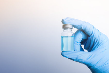 Doctor holding vial with medication on light background, closeup view and space for text. Vaccination and immunizationの写真素材
