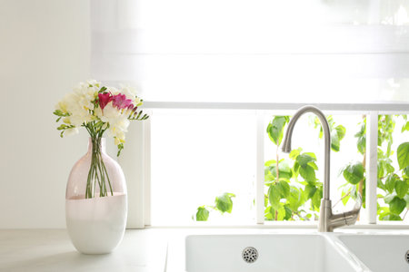 Beautiful bouquet of freesia flowers on countertop in kitchenの写真素材