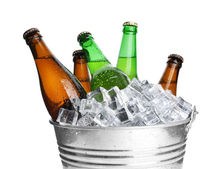Metal bucket with bottles of beer and ice cubes isolated on whiteの写真素材